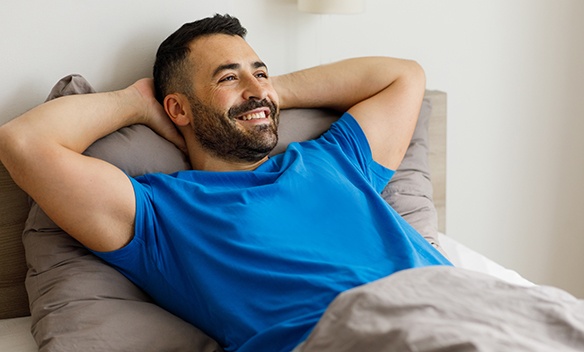 Well-rested man in blue t-shirt lying in bed