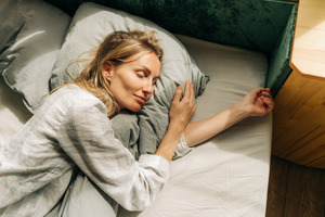 Woman in grey shirt sleeping in bed